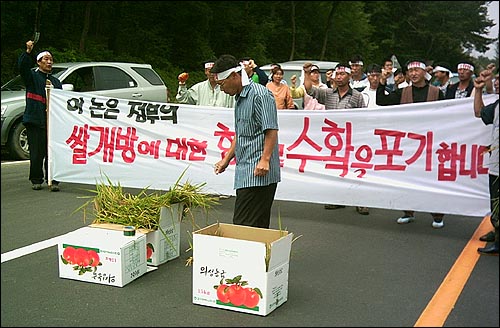 의성지역 6개 농민단체 회원 등 70여명의 농민과 대학생들이 논을 갈아엎은 후 흙과 벼나락을 사과상자에 담아놓고 구호를 외치고 있다. 